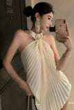 Woman taking a mirror selfie wearing a beige pleated dress.