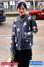 Woman wearing a blue cardigan with white patterns on a street background