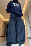 Person wearing a navy hoodie and wide-leg jeans in a modern indoor setting
