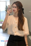 Woman taking a mirror selfie wearing a light-colored blouse with lace details.