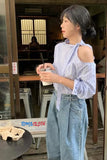 Woman holding a drink in a casual setting with 'Tomecloth' branding.