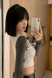 Person taking a mirror selfie wearing a gray long-sleeve top over a white crop top.