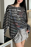 Person wearing a black and white striped sweater with colorful text and gray shorts indoors.