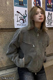 Person wearing a brown jacket leaning against a wall with posters.