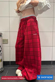 Person wearing red plaid pants with a visible brand logo in a bathroom setting.