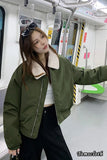 Woman wearing a green jacket with a white interior on a subway train.