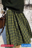 Person wearing a green plaid skirt with a blurred snowy background