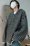 Person wearing a black and white striped coat in a room with a mirror.
