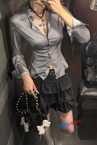 Person wearing a striped shirt and black skirt with a handbag, sitting inside a vehicle.