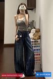 Person wearing a gray tank top and blue jeans taking a mirror selfie in a room with teddy bears and a color swatch.