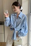 Woman in a light blue shirt holding a glass in a kitchen setting