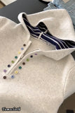 Close-up of a beige garment with colorful buttons and a striped lining.