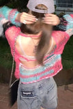 Person wearing a colorful sweater with cut-out design and denim shorts.