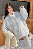 Woman wearing a white textured sweater with colorful buttons in a snowy outdoor setting.