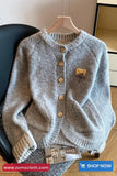 Gray knitted cardigan with a bear patch on a hanger, brand 'Toms Cloth' visible.
