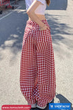 Person wearing red and white checkered pants on a street.