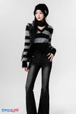 Person wearing a black and gray striped sweater, black pants, and a black beanie on a white background.