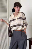 Person wearing a striped sweater and gray pants with a leopard print cap indoors.