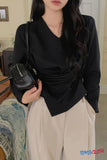 Person wearing a black top and beige pants holding a black handbag indoors.