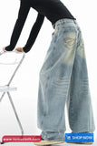 Person wearing light blue wide-leg jeans standing on a white background with 'tomscloth' branding.