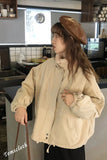 Woman wearing a beige jacket and brown beret in a kitchen setting