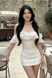 Woman in a white dress standing outdoors with a stone wall background