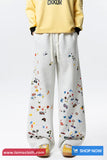 White pants with colorful patterns worn by a person in a yellow hoodie on a white background.