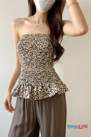 Woman wearing a leopard print strapless top and brown pants against a plain background