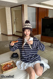 Person sitting on a couch holding a pizza in a modern living room.