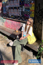 Woman sitting on a bench with a colorful background of posters and graffiti.