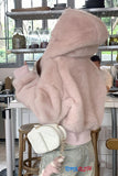 Person wearing a fluffy pink hooded jacket in a cafe setting