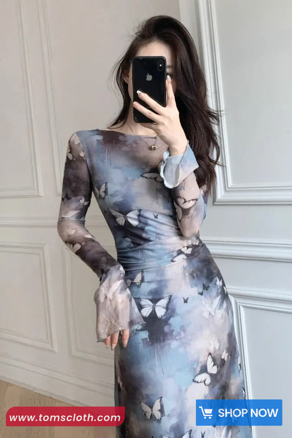 Woman wearing a butterfly-patterned dress taking a mirror selfie.