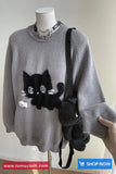 Gray sweater with black cat design on a mannequin, held by a hand.