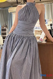 Woman wearing a gray and white striped halter neck dress in an indoor setting.