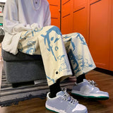 Person sitting on a chair wearing light-colored pants with blue designs and matching sneakers in a room with orange lockers.