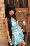 Person wearing a blue and white striped dress leaning against a textured wall.