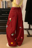 Red pants with floral embroidery worn by a person in a room.