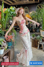 Woman in a floral dress standing in a plant-filled indoor setting with 'tomscloth.com' branding.