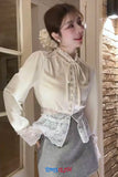 Woman wearing a white blouse with lace details in a room with brick walls.