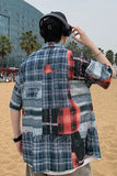 Person wearing a plaid shirt with abstract designs on a beach