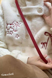 White textured fabric with red embroidery and a hand holding a red strap.