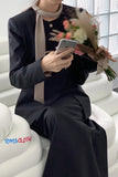 Person in a black outfit holding flowers and a phone on a white couch with 'TOMS CLOTH' branding.