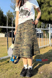 Person wearing a camouflage skirt and white t-shirt with graphic design outdoors.