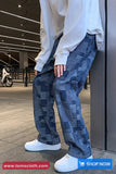 Person wearing blue checkered pants and white sneakers in an urban setting with 'tomscloth.com' branding.