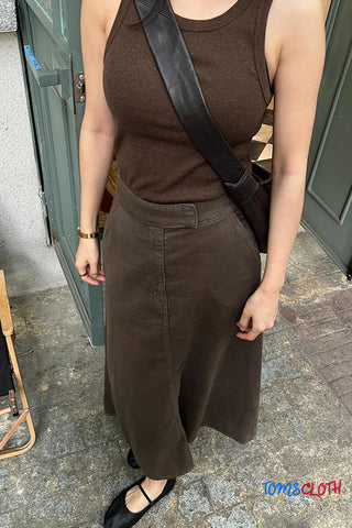 Person wearing a brown sleeveless top and wide-leg pants standing outdoors.