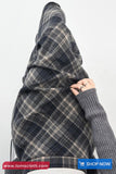 Person wearing a plaid blanket draped over their shoulders with 'tomscloth.com' branding.