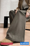 Person wearing pinstripe pants sitting on a chair with a minimal background