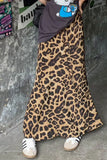 Person wearing a leopard print skirt with a dark top and white sneakers on a gray pavement.