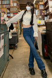 Person wearing a white blouse, blue jeans, and black shoes in a bookstore.
