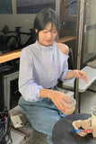 Woman sitting at a table in a casual setting, holding a drink.